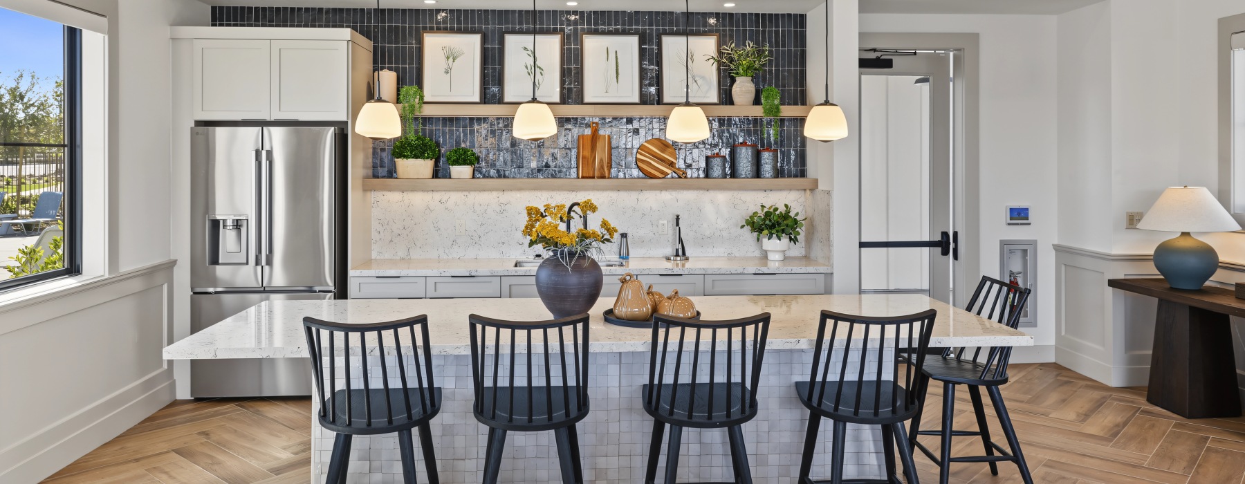 Haven clubhouse kitchen with a large island, bar seating, pendant lighting, and a stainless steel refrigerator.