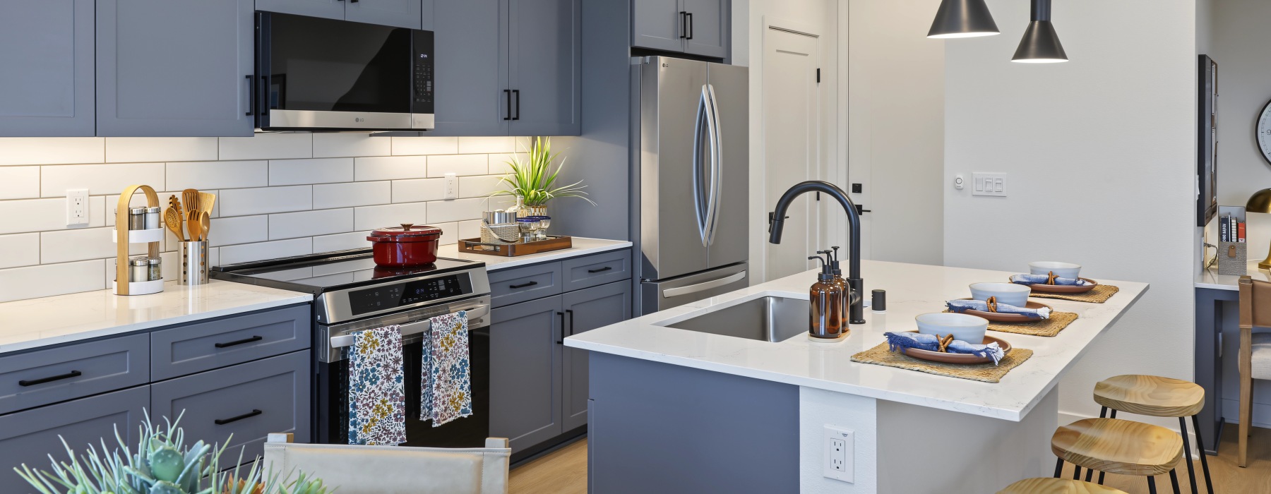 Kitchen at Haven with dark cabinets, stainless steel appliances, and an island with a sink and bar seating.