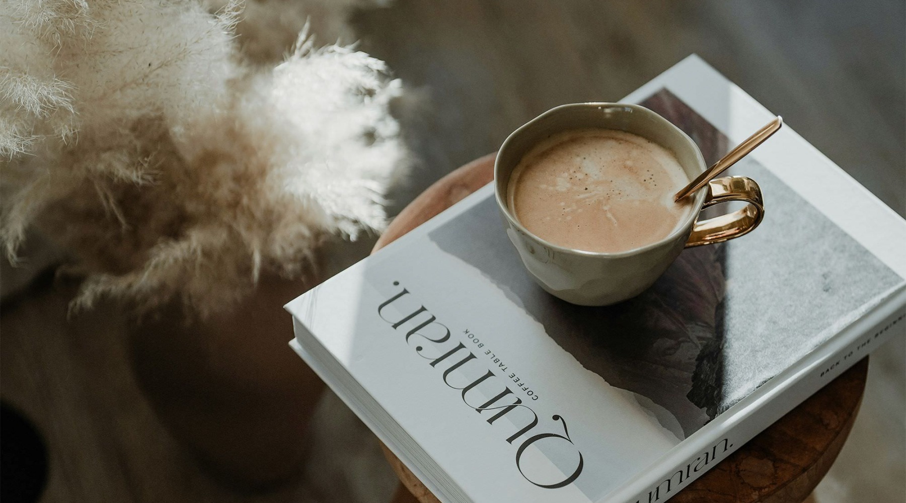 a cup of coffee on a book on a stool in a living room